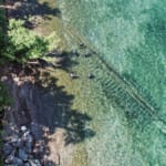Aerial view of divers exploring shipwreck in clear turquoise water