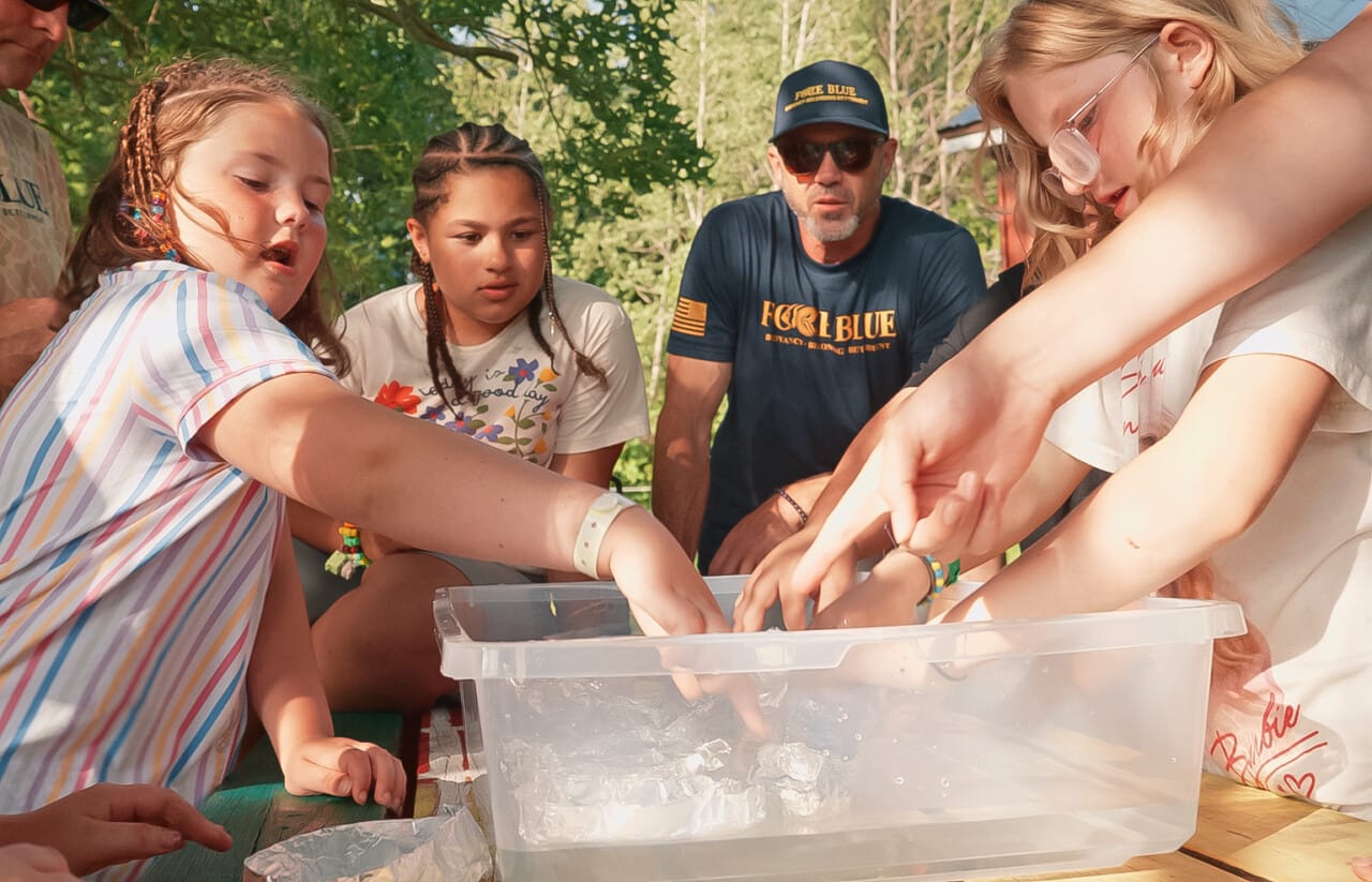 Children and adult exploring water activity at outdoor camp