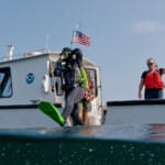NOAA diver entering water from research boat with dive flag