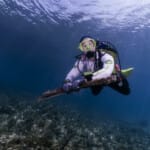 Scuba diver holding debris underwater during ocean cleanup dive