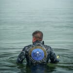 Diver in NOAA National Marine Sanctuaries wetsuit entering ocean