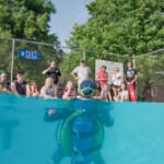 Scuba diver in pool with group of kids watching poolside