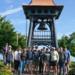 Group of people posing in front of historic bell tower