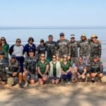 Large group of Force Blue team members posing on beach