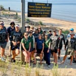 Group posing at Lakeview Sand Dune Walkover Habitat Restoration sign