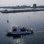 NOAA research boat navigating calm harbor waters near industrial port