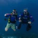 Two scuba divers posing underwater near coral reef