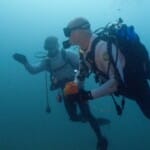 Two scuba divers swimming underwater with diving gear