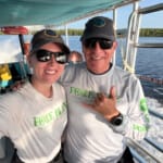 Two smiling people in Fore Blue shirts on a boat