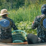 Two NOAA Force Blue team members in canoe among marsh reeds