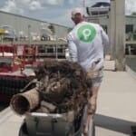 Man hauling marine debris at a harbor dock