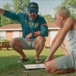 Adult man instructing child outdoors using a map or board