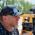Man using DeWalt builder's level surveying instrument outdoors